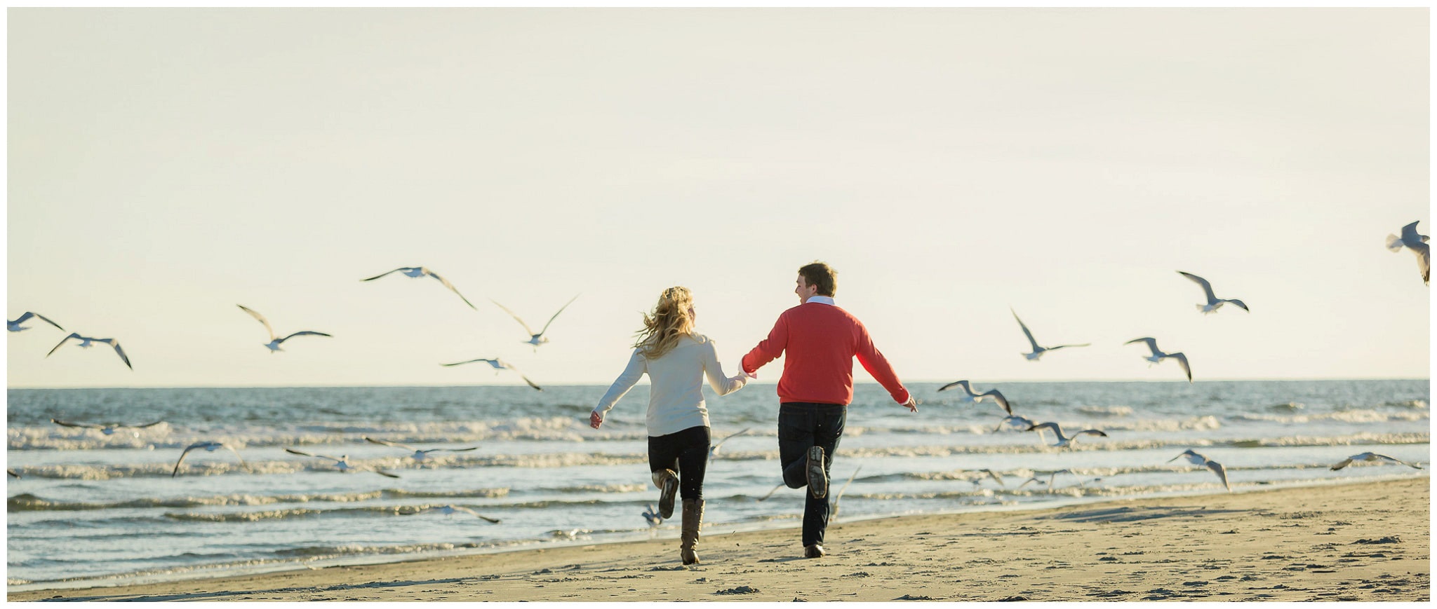 Couple running on the beach and chasing seaguls 