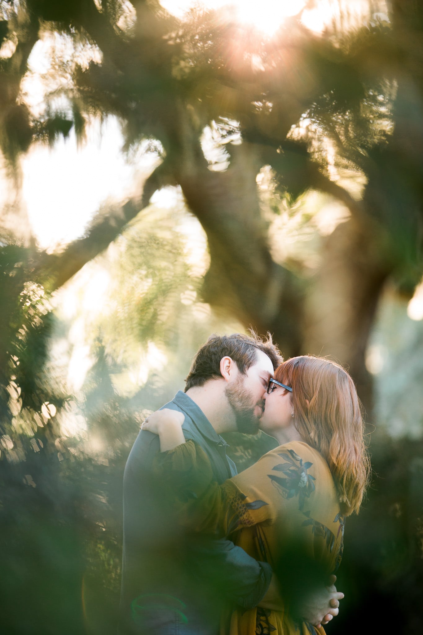 Brian and Kelsey kissing as viewed through leaves, Caledonia Golf and Fish Club, Myrtle Beach Engagement Session 19, www.onelifephoto.net