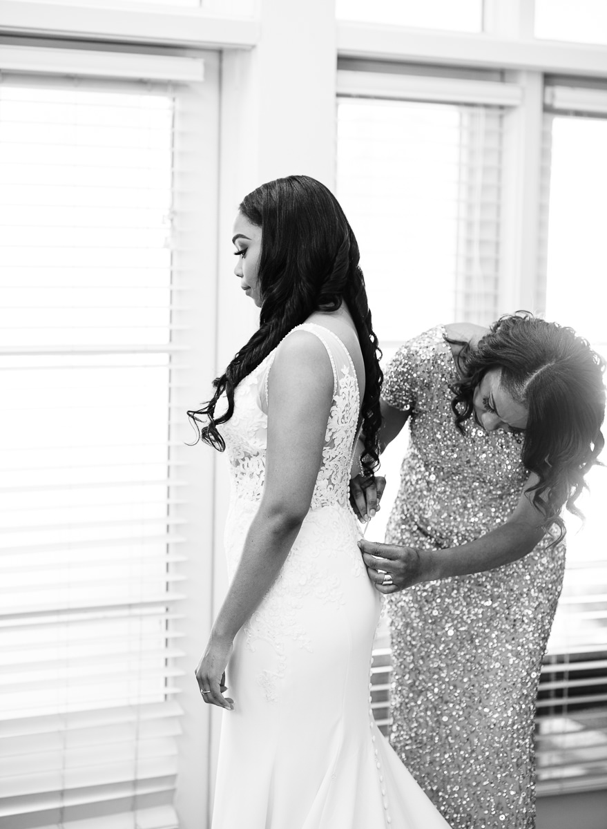 mother helping bride with the dress